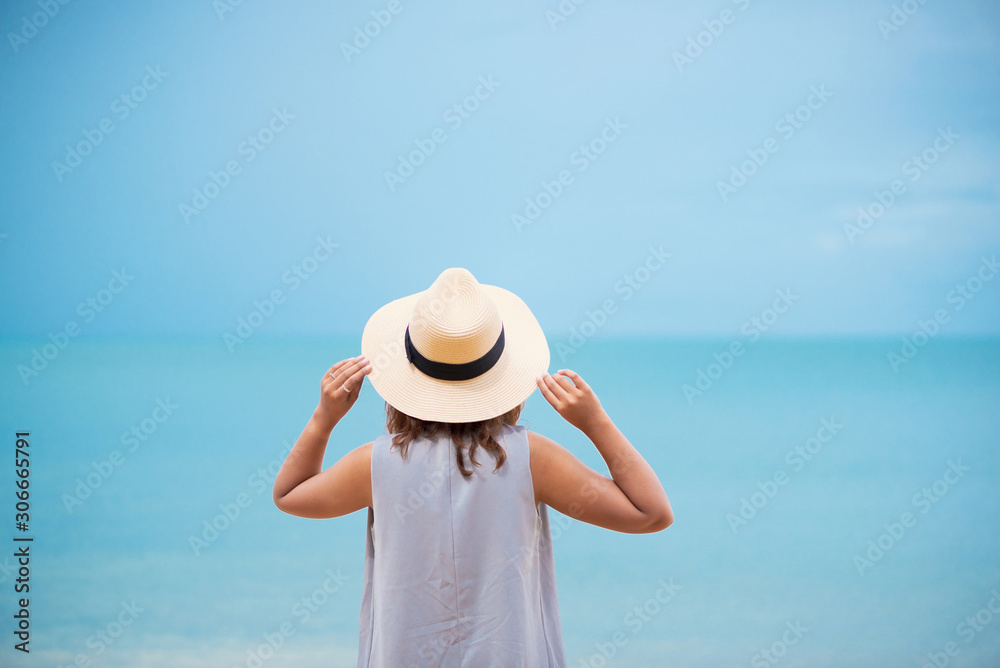 Woman with straw hat relaxing on the beach.