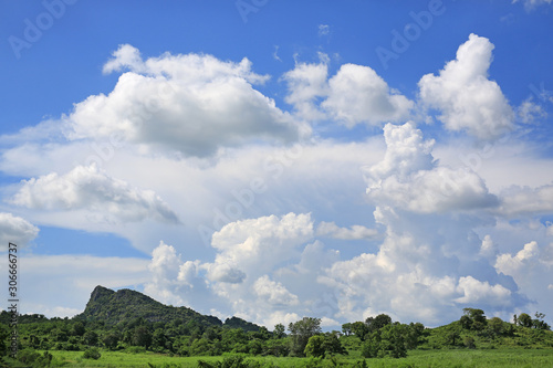 Blue sky and fluffy clouds with green field background. Mountain and meadow landscape background.