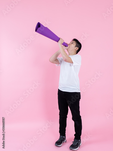 Asian preteen boy using purple paper megaphone on pink background.