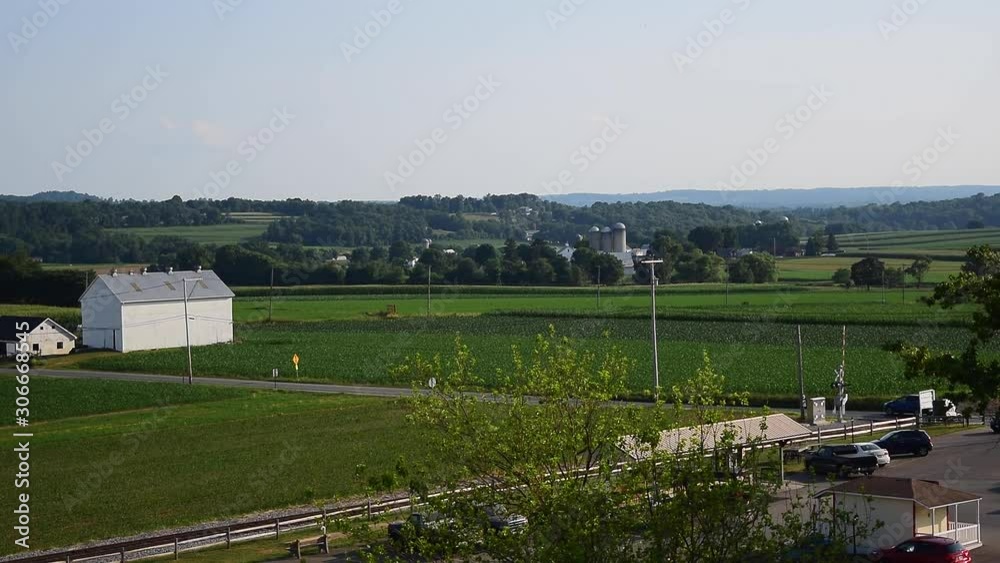 Overlooking view of countryside with farmland and farms with cars passing by Overlooking view of countryside with farmland and farms with cars passing by