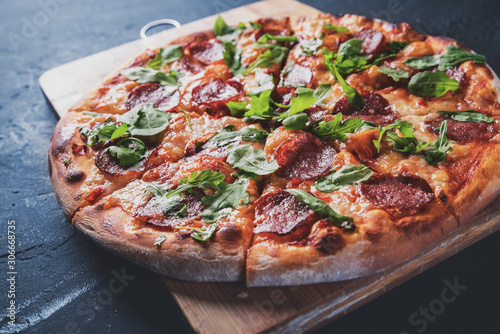 Pepperoni Pizza with Mozzarella cheese, salami, Tomato sauce, pepper, Spices and Fresh arugula. Italian pizza on Dark grey black slate background