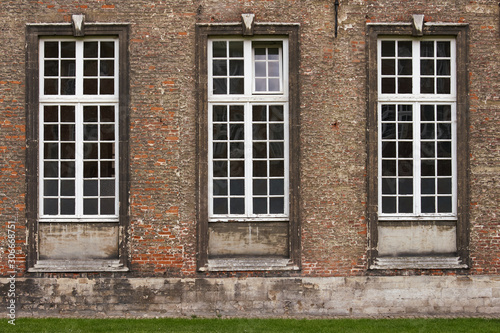 Three grunge windows on an old building with red bricks