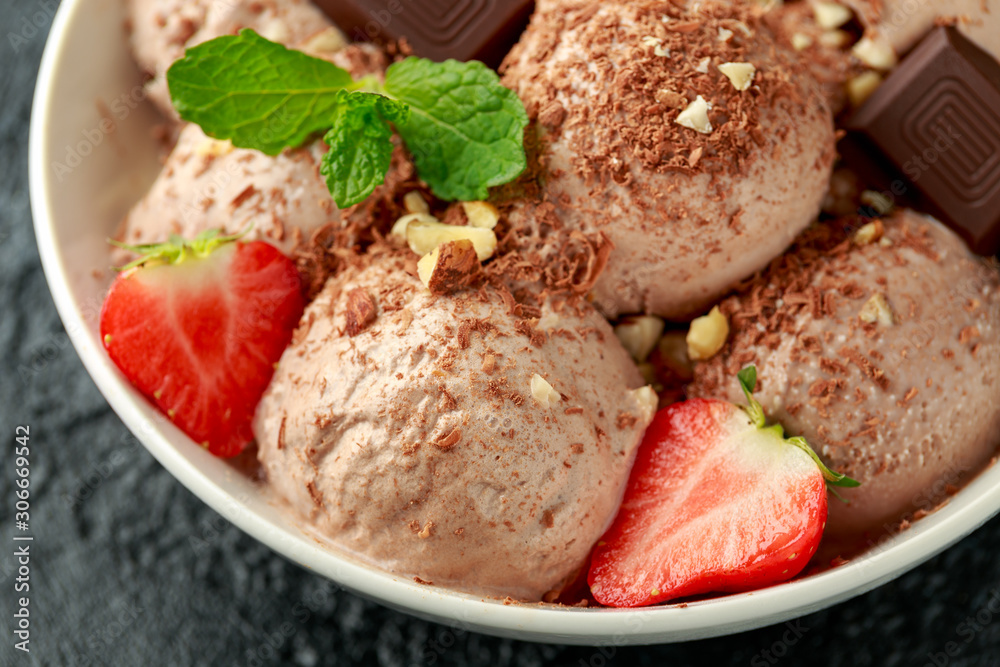Chocolate Ice Cream with dark chocolate bars, strawberry and hazelnuts in a white bowl