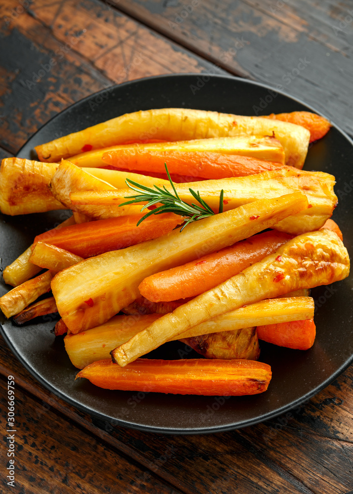 Roasted Parsnips and Carrots with herbs on rustic wooden table Roasted Parsnips and Carrots with herbs on rustic wooden table