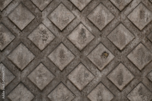 Texture of rhombus on the surface of a grey cement background with rust and smudges and scratches.