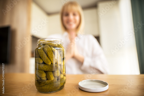Pregnant woman eating pickles in kitchen