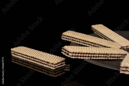 Group of five whole sweet chocolate biscuit wafer on gray ceramic plate isolated on black glass