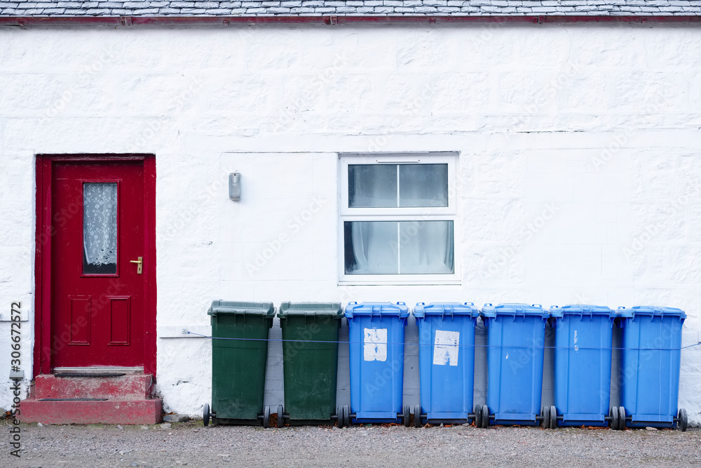 Naklejka premium Blue green coloured wheelie bins in a row outside house waiting for bin men to collect oil rural countryside UK