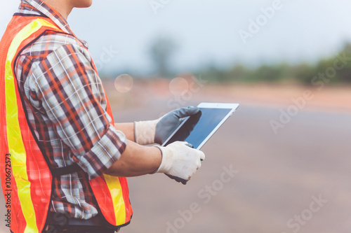 Asian engineer with hardhat using tablet inspecting and working at construction site