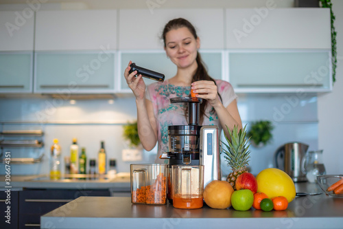 Fotografía Woman making fruit juice using juicer machine in home kitchen, healthy eating li