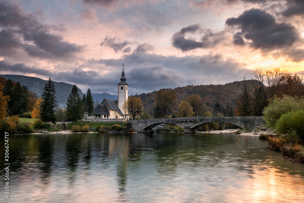 Lake Bohinj Church during sunrise in fall season Slovenia Triglav National Park