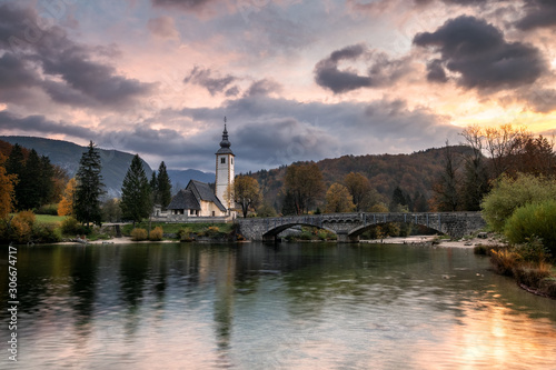 Lake Bohinj Church during sunrise in fall season Slovenia Triglav National Park