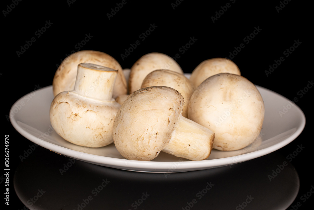 Lot of whole fresh white champignon on white ceramic plate isolated on black glass Lot of whole fresh white champignon on white ceramic plate isolated on black glass