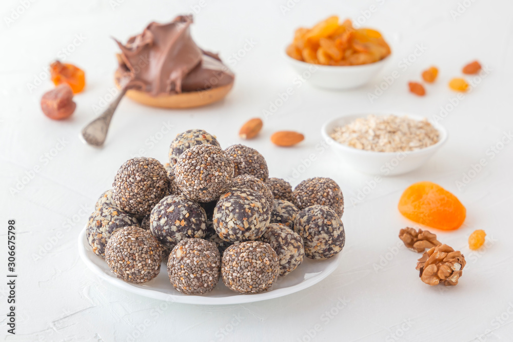 Natural healthy raw energy bites, chocolate paste and mix of dried fruits with nuts on a white table. Close-up Natural healthy raw energy bites, chocolate paste and mix of dried fruits with nuts on a white table. Close-up