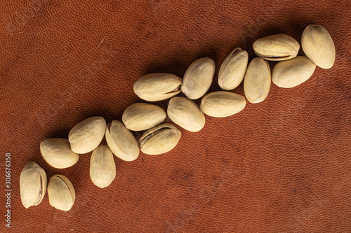 Lot of whole salted pistachio flatlay on cognac leather photo