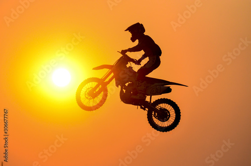 Practice day silhouette of a motorcycle motocross jumping on sunset background.