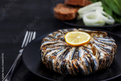 Pilaf with hamsi anchovy fish. Traditional Turkish food - Kapama Pilav - on black wooden table. photo