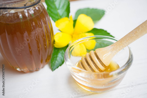 Sweet honey in jar with honey scoop on a bolw.
