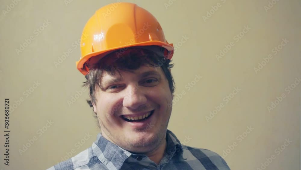 funny emotional middle aged man in a construction helmet looks at the camera in surprise and attentively.humorous video portrait of a builder
