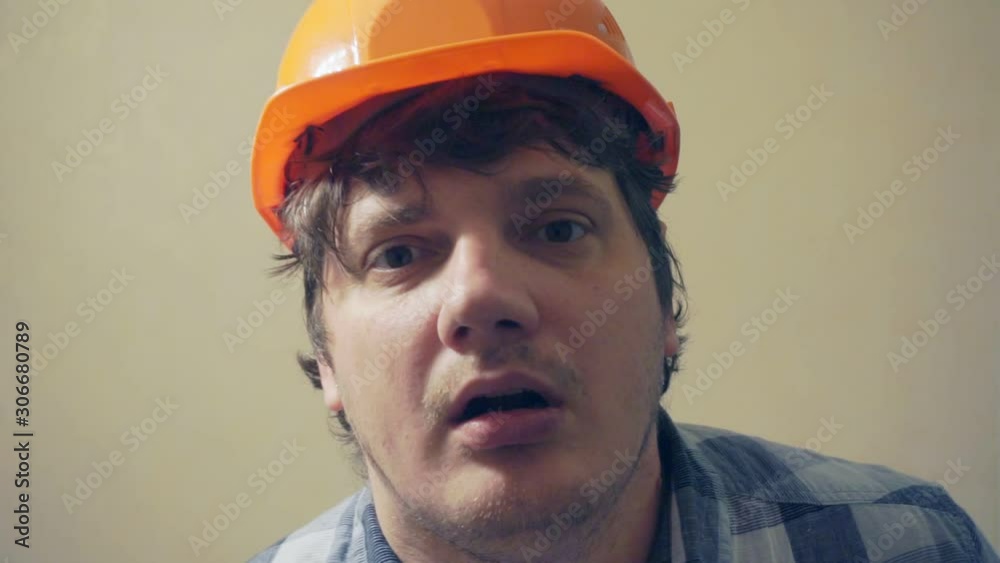 funny emotional middle aged man in a construction helmet looks at the camera in surprise and attentively.humorous video portrait of a builder funny emotional middle aged man in a construction helmet looks at the camera in surprise and attentively.humorous video portrait of a builder