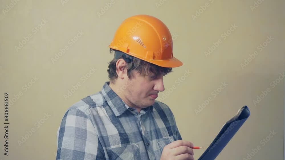 cheerful middle aged man in a construction helmet holds a folder with documents.video portrait of a builder at work cheerful middle aged man in a construction helmet holds a folder with documents.video portrait of a builder at work