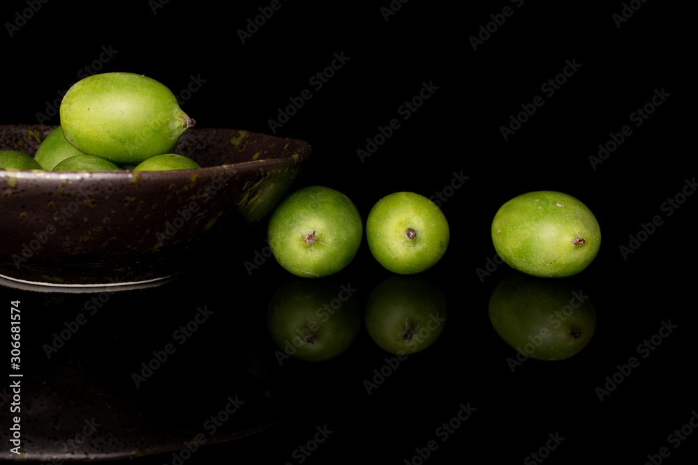Lot of whole hardy green kiwi in glazed bowl isolated on black glass Lot of whole hardy green kiwi in glazed bowl isolated on black glass