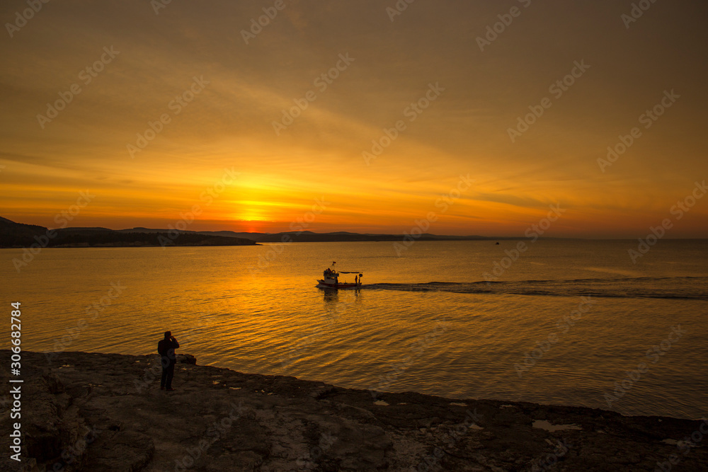 Orange sunset, boat and the people on the beach