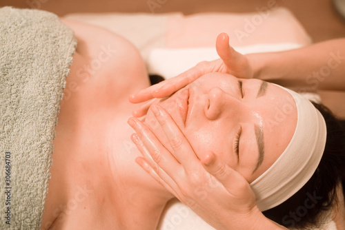 Beautiful young woman getting a face massage treatment at beauty salon