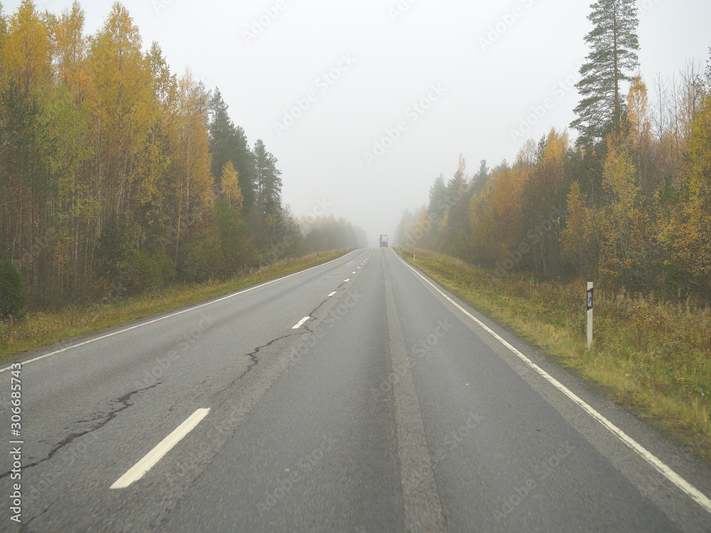 Autumn driving on wet road through forests in Finland