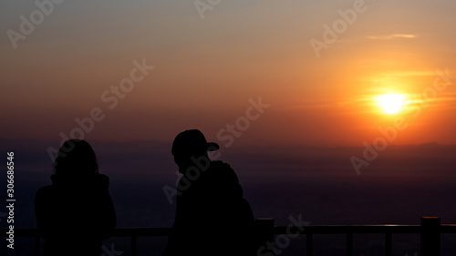 Silhouette of a couple at sunrise with the sun in the background.