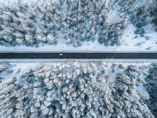 Aerial view of winter road and forest with snow covered trees in Finland
