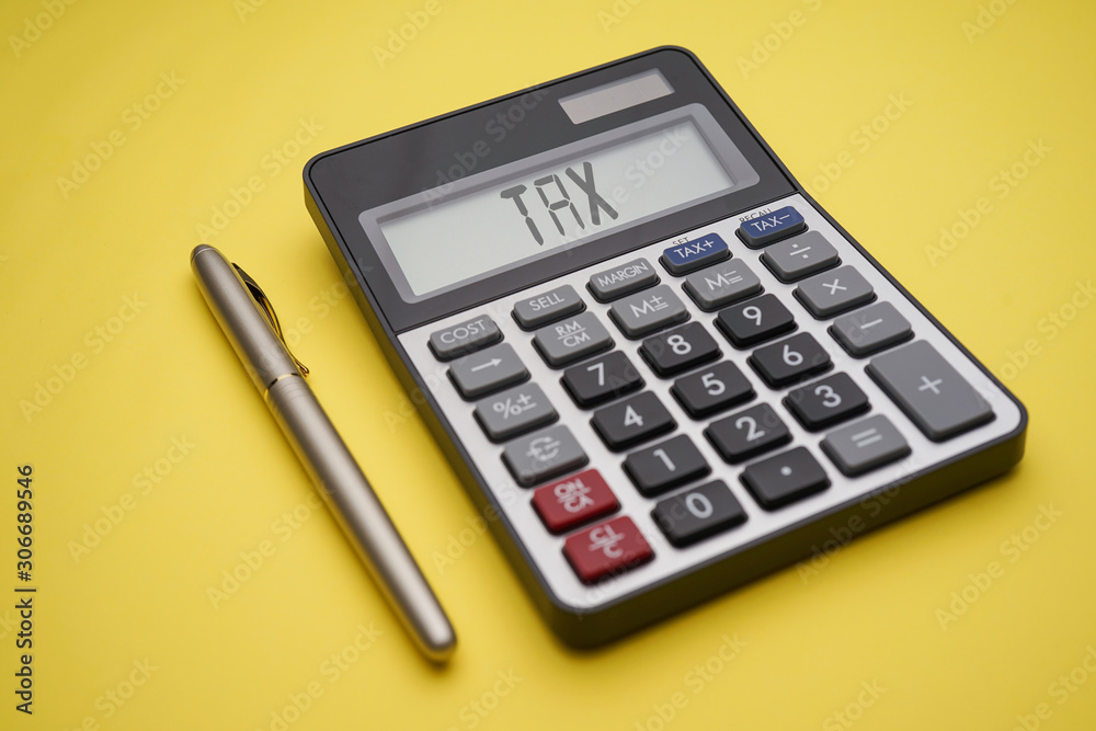 Tax Time conceptual with calculator and gold pen on yellow background Tax Time conceptual with calculator and gold pen on yellow background