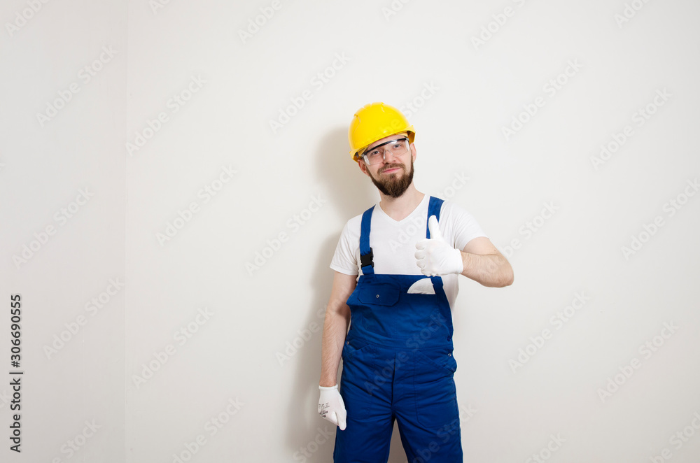 Handy man showing thumbs up standing next to white wall indoors Handy man showing thumbs up standing next to white wall indoors