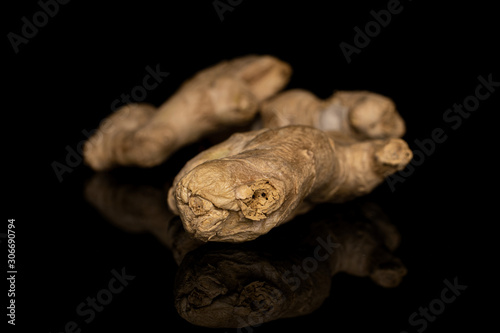 Group of two whole fresh brown ginger front focus isolated on black glass