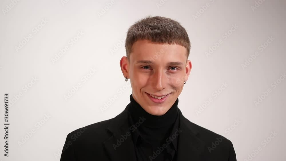 portrait of young man with earrings that smiling and looking at the camera, emotions, isolated on white background portrait of young man with earrings that smiling and looking at the camera, emotions, isolated on white background