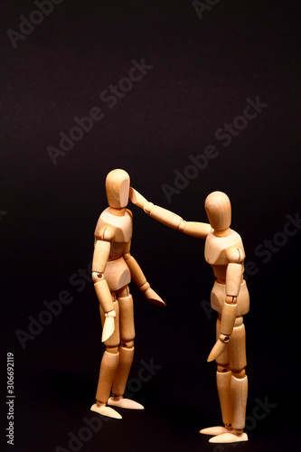 Conceptual image of a wooden manikin hitting another