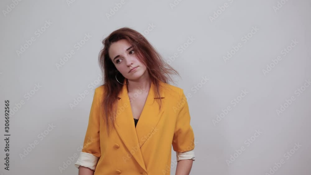 Unhappy young woman in yellow jacket looking dissatisfaction, keeping hand on head loke gun isolated on gray background in studio. People sincere emotions, lifestyle concept. Unhappy young woman in yellow jacket looking dissatisfaction, keeping hand on head loke gun isolated on gray background in studio. People sincere emotions, lifestyle concept.
