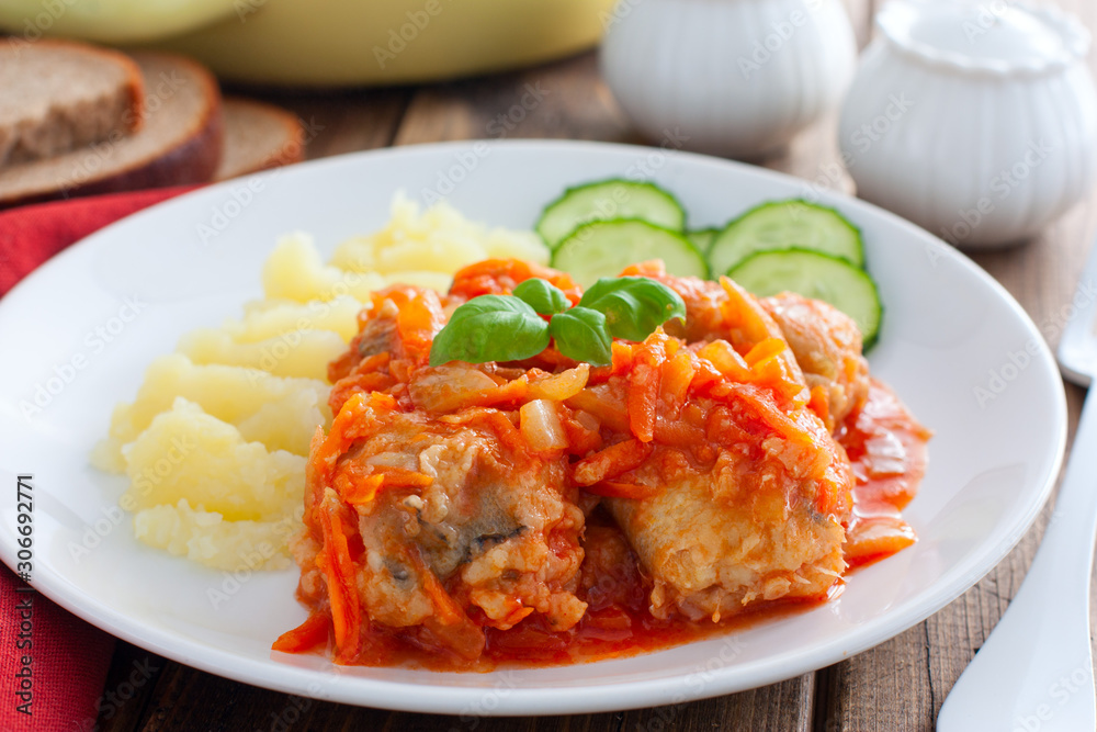 Pollock in tomato marinade with onions and carrots on a white plate with mashed potatoes, selective focus Pollock in tomato marinade with onions and carrots on a white plate with mashed potatoes, selective focus