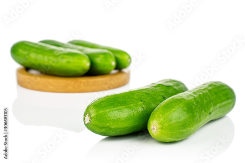Group of five whole fresh green baby cucumber on bamboo coaster isolated on white background