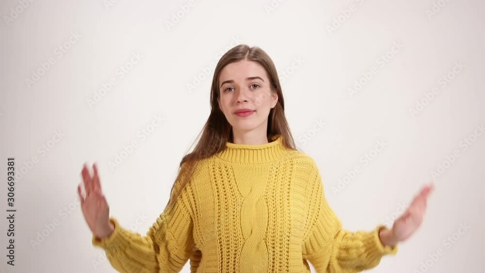 Girl in a yellow sweater cannot make a choice, two bowls of scales, nods her head white background Girl in a yellow sweater cannot make a choice, two bowls of scales, nods her head white background