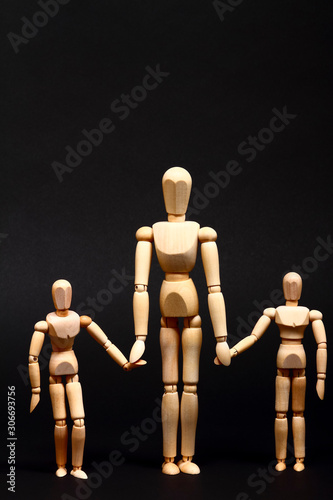 Conceptual image of a wooden manikin parent and children holding hands