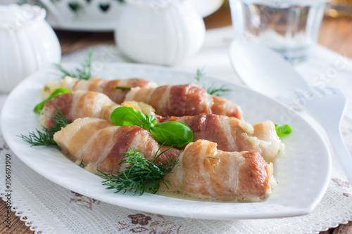 Oven bacon rolls with cheese baked on a white dish, horizontal
