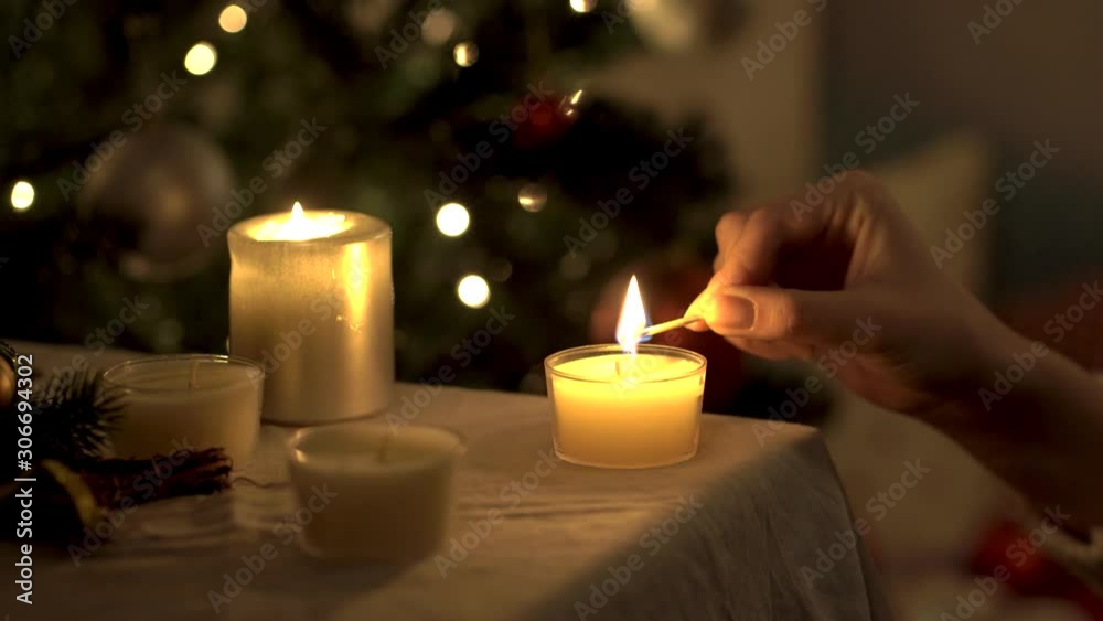girl is lighting a candle in a Christmas decoration. Close up. New Year holidays concept. girl is lighting a candle in a Christmas decoration. Close up. New Year holidays concept.