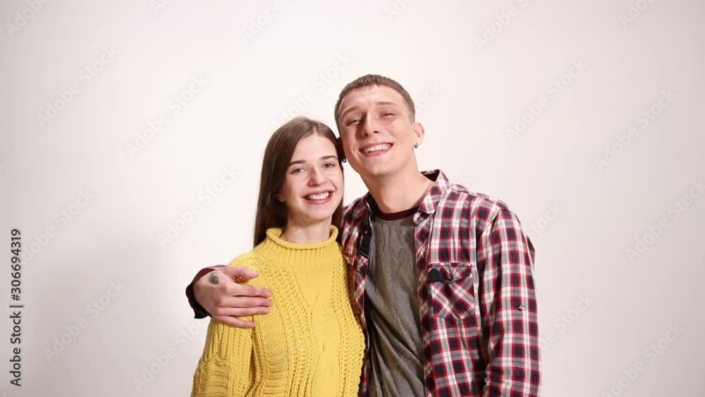 Young beautiful couple hugs and laughs on the white background wall Young beautiful couple hugs and laughs on the white background wall