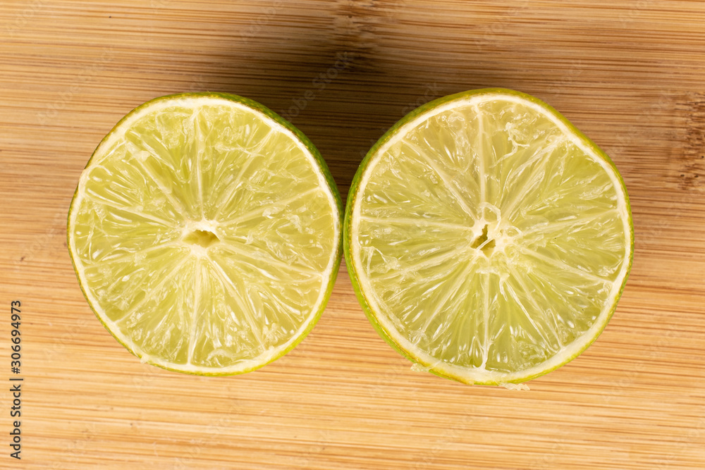 Group of two halves of sour green lime flatlay on light wood Group of two halves of sour green lime flatlay on light wood