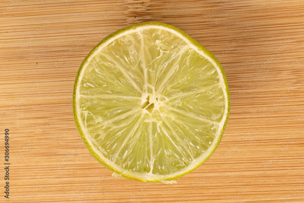 One half of sour green lime flatlay on light wood One half of sour green lime flatlay on light wood