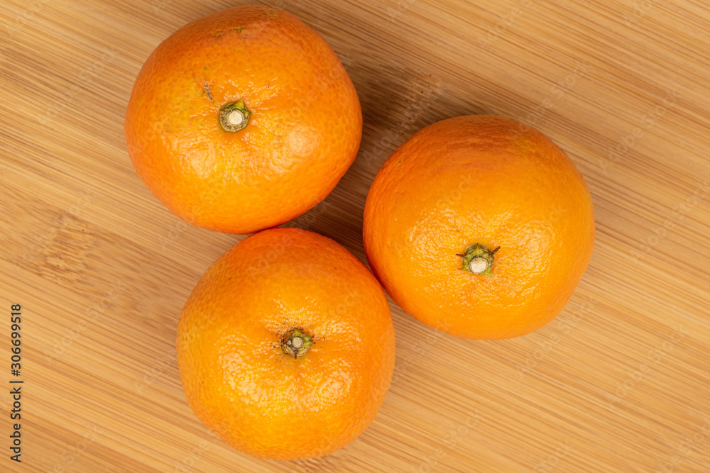 Group of three whole fresh orange mandarin flatlay on light wood Group of three whole fresh orange mandarin flatlay on light wood