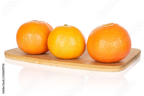 Group of three whole fresh orange mandarin on bamboo cutting board isolated on white background