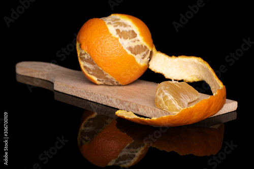 Group of one whole one piece of fresh orange mandarin on wooden cutting board isolated on black glass