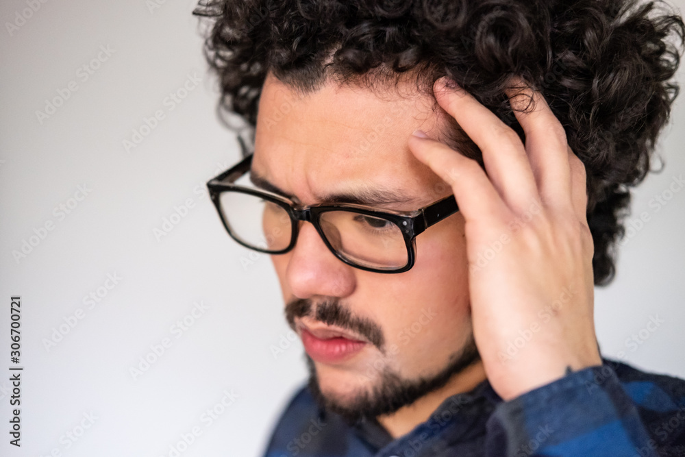 Obraz premium Latin American man with curly hair having a headache, upset expression, on a white background 